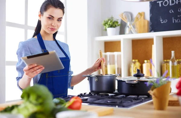 Junge Frau kocht mit Tablet-Computer in ihrer Küche — Stockfoto