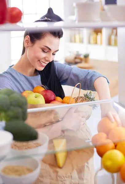 Smiling woman taking a fresh fruit out of the fridge, healthy food concept — Stock Photo, Image