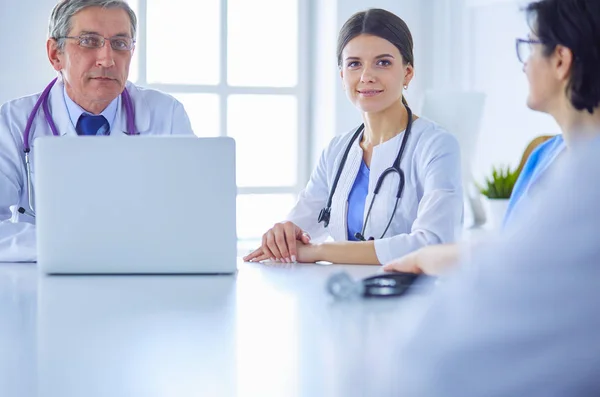 Serieuze medische team met behulp van een laptop in een heldere consulting room — Stockfoto