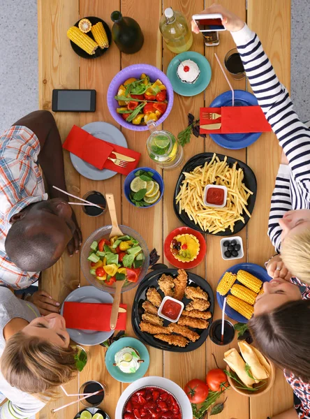 Vue du dessus du groupe de personnes qui dînent ensemble tout en étant assis à une table en bois. De la nourriture sur la table. Les gens mangent fast food. — Photo