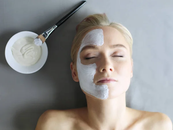 Mască de feță.Frumoasă fată tânără la spa, cosmetician femeie care aplică mască facială . — Fotografie, imagine de stoc