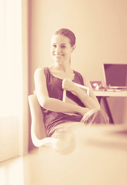 Ung kvinna sitter vid skrivbordet med instrument, plan och laptop. — Stockfoto