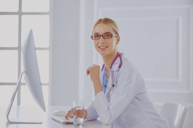 Hastanede masasında oturan genç bir kadın doktorun portresi.