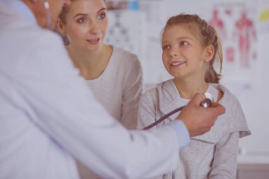 Steteskoplu kız ve doktor kalp atışlarını dinliyor.