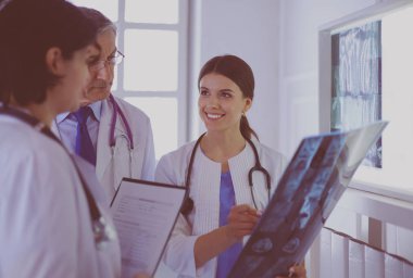 Hastanedeki röntgenlere bakarak hastaların teşhisini tartışan gülümseyen doktorlar