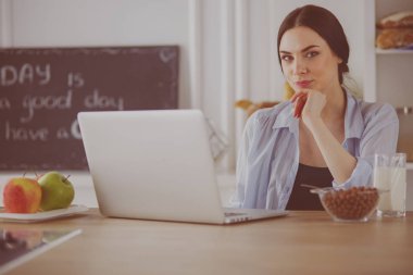 bir fincan kahve ve bir dizüstü bilgisayar mutfakta bir kadınla