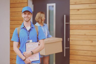 Mavi üniformalı gülümseyen kurye servis konseptine paket kutusu teslim eden teslimatçı. Mavi üniformalı gülümseyen teslimatçı.