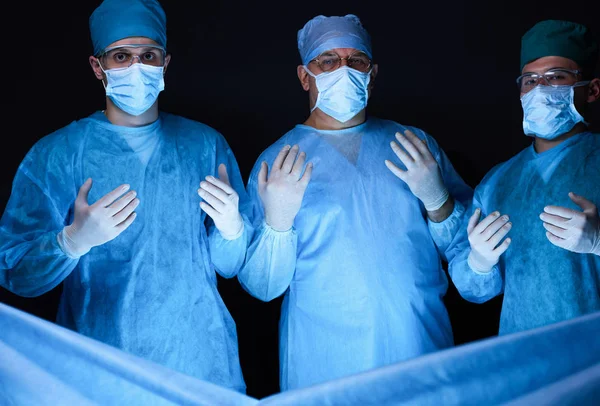 Grupo de cirurgiões no trabalho em sala de operações tonificada em azul. Equipe médica realizando operação — Fotografia de Stock