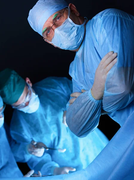 Ameliyathanede çalışan bir grup cerrah mavi tonda çalışıyor. Tıbbi ekip operasyon yapıyor. — Stok fotoğraf