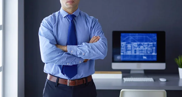 Hombre de negocios sonriente con touchpad de pie en el lugar de trabajo en la oficina — Foto de Stock