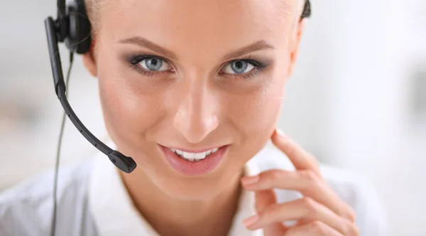 Porträt einer hübschen jungen Bedienerin, die mit Headset am Schreibtisch sitzt — Stockfoto