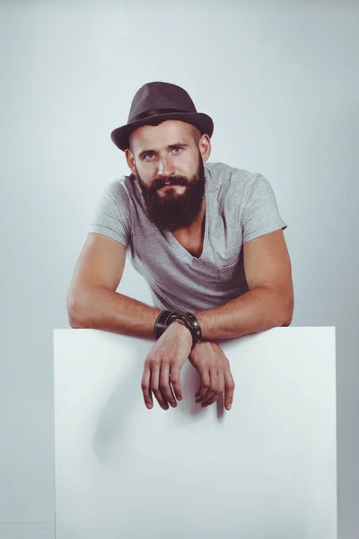 Young man standing in hat by blank whiteboard — Stock Photo, Image