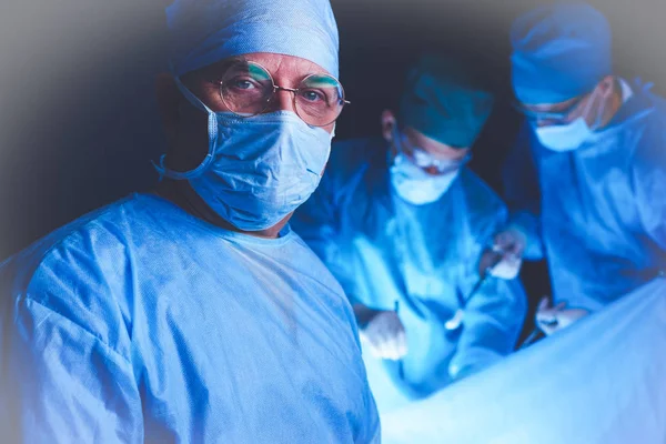 Groupe de chirurgiens au travail en salle d'opération tonique en bleu. Équipe médicale effectuant l'opération — Photo