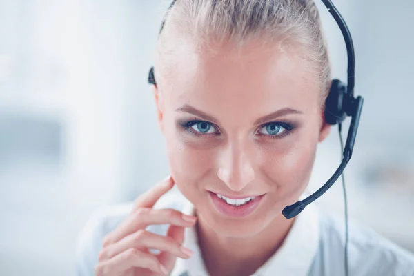 Portret van mooie jonge vrouwelijke operator zittend aan bureau met headset — Stockfoto