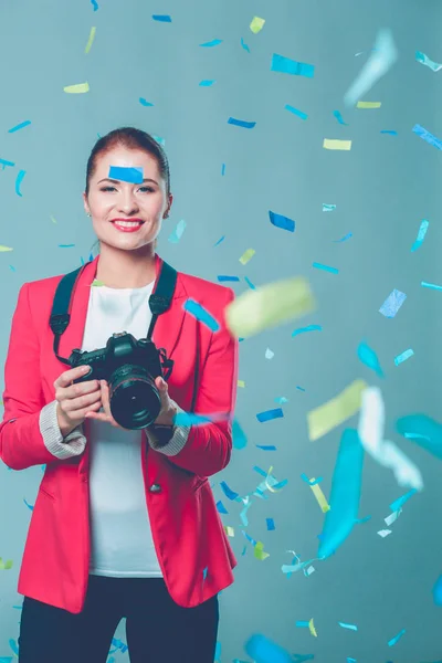 Beautiful happy woman with camera at celebration party with confetti . Birthday or New Year eve celebrating concept — Stock Photo, Image