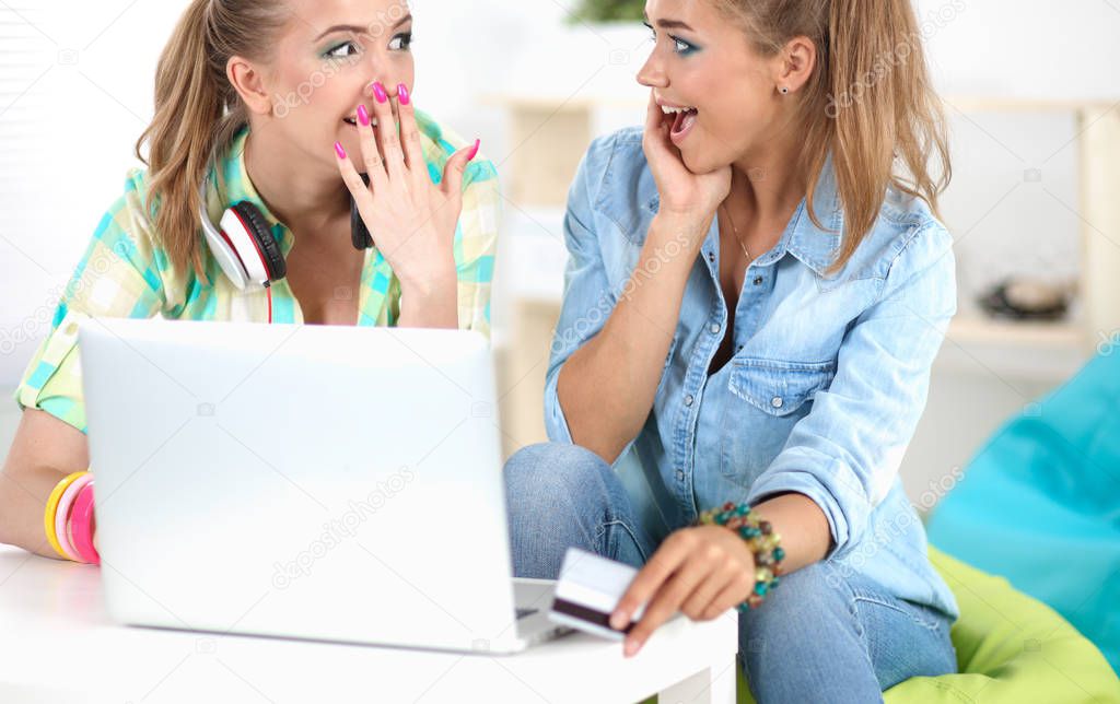 Two friends buying on line with credit card and a laptop