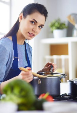 Mutfakta ahşap kaşıkla yemek pişiren kadın