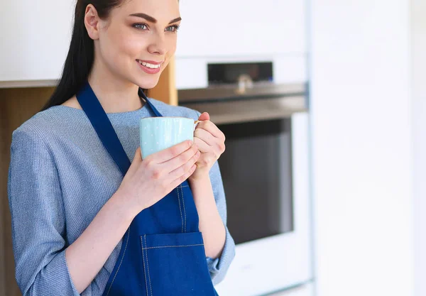 Портрет молодой женщины с чашкой на кухонном фоне — стоковое фото
