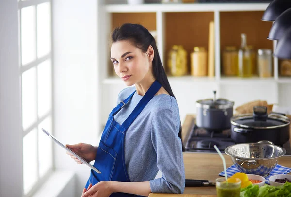 Jeune femme utilisant une tablette informatique pour cuisiner dans sa cuisine — Photo