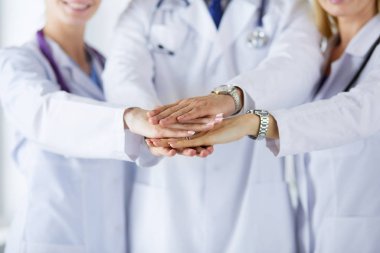 Doktorlar ve hemşireler tıbbi bir ekipte el ele tutuşuyorlar.