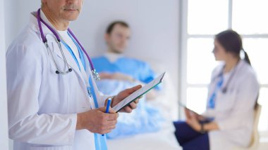 Doktor bir hastanın ve doktorun önünde klasörü tutuyor.