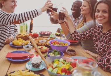 Ahşap masada otururken birlikte yemek yiyen bir grup insanın üst düzey görüntüsü. Masada yemek var. İnsanlar fast food yiyor..