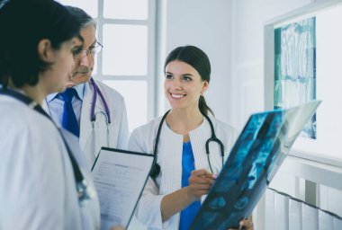Hastanedeki röntgenlere bakarak hastaların teşhisini tartışan gülümseyen doktorlar
