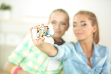 Kadınlar selfie çekiyor. İki çekici genç kadın selfie çekiyor ve gülümsüyor.