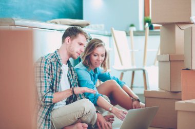 Genç bir çift yeni ev içinde hareket. Oturma ve açma sonra rahatlatıcı. Bir şey üstünde laptop arıyorum. Genç Çift