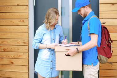Mavi üniformalı gülümseyen kurye servis konseptine paket kutusu teslim eden teslimatçı. Mavi üniformalı gülümseyen teslimatçı.