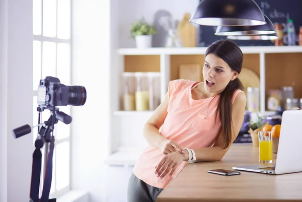 Ung kvinna i köket med bärbar dator ser recept, leende. Begreppet livsmedelsbloggare — Stockfoto