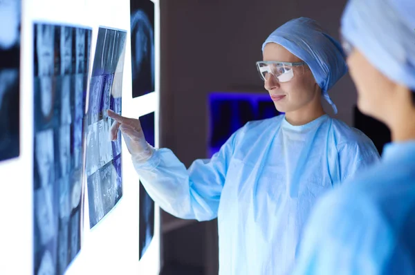 Arzt im Krankenhaus sitzt am Schreibtisch und betrachtet Röntgenbilder auf Tablet vor weißem Hintergrund mit Röntgenaufnahmen — Stockfoto