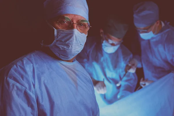 Gruppo di chirurghi al lavoro in sala operatoria tonica in blu. Equipe medica che esegue l'operazione — Foto Stock
