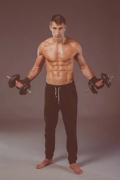 Schöner muskulöser Mann, der mit Hanteln trainiert. persönlicher Fitnesstrainer. Persönliches Training. — Stockfoto