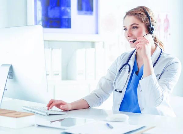 Young practitioner doctor working at the clinic reception desk, she is answering phone calls and scheduling appointments — Stock Photo, Image