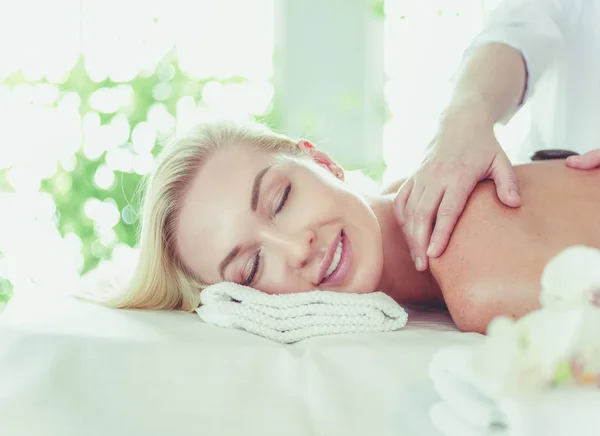 Jovem mulher no salão de spa, recebendo pedras massagem — Fotografia de Stock