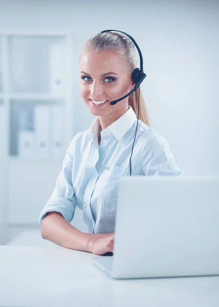 Portrait of pretty young female operator sitting at office desk with headset — Stock Photo, Image