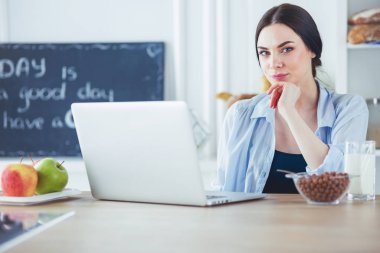 bir fincan kahve ve bir dizüstü bilgisayar mutfakta bir kadınla