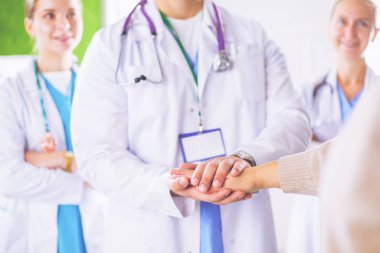 Doktorlar ve hemşireler tıbbi bir ekipte el ele tutuşuyorlar.