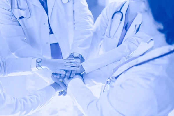 Orvosok és nővérek egymásra rakják a kezüket. Fehér alapon elszigetelve — Stock Fotó