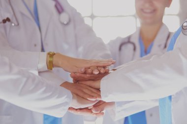 Doktorlar ve hemşireler tıbbi bir ekipte el ele tutuşuyorlar.