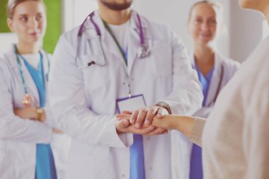 Doktorlar ve hemşireler tıbbi bir ekipte el ele tutuşuyorlar.