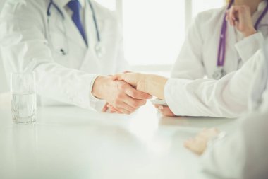 Doktor ofiste erkek bir hastayla el sıkışıyor.
