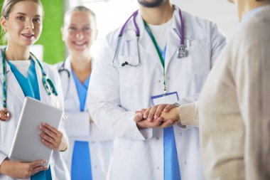 Doktorlar ve hemşireler el ele tutuşuyor. Beyazda izole edilmiş