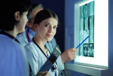 Bir grup doktor bir klinikte röntgenleri inceliyor, teşhis koymayı düşünüyorlar.