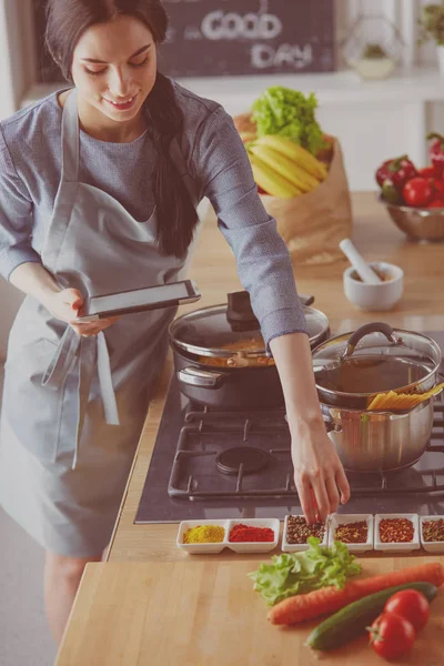 Donna che cuoce a casa seguendo la ricetta su una tavoletta — Foto Stock