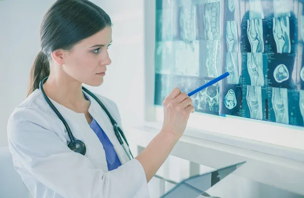 Jeune femme médecin souriante avec stéthoscope pointant vers la radiographie au cabinet des médecins — Photo