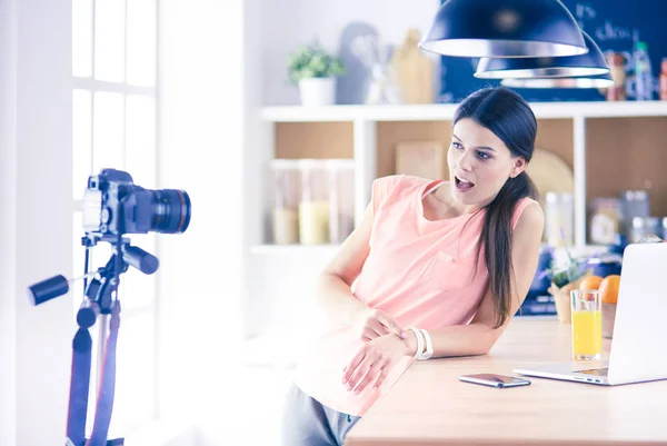 Ung kvinna i köket med bärbar dator ser recept, leende. Begreppet livsmedelsbloggare — Stockfoto