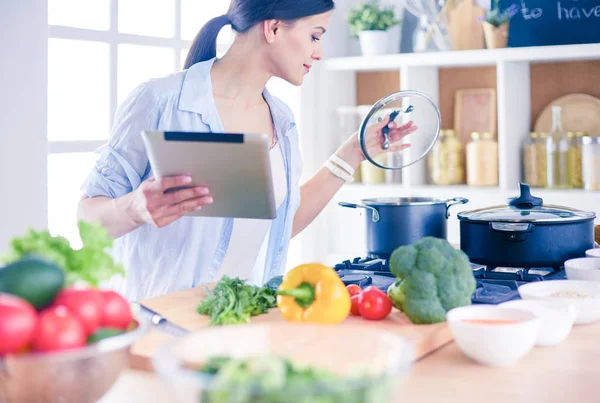 Junge Frau kocht mit Tablet-Computer in ihrer Küche. — Stockfoto