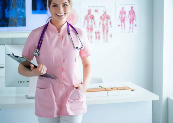 Sorridente medico donna con una cartella in uniforme in piedi in ospedale — Foto Stock